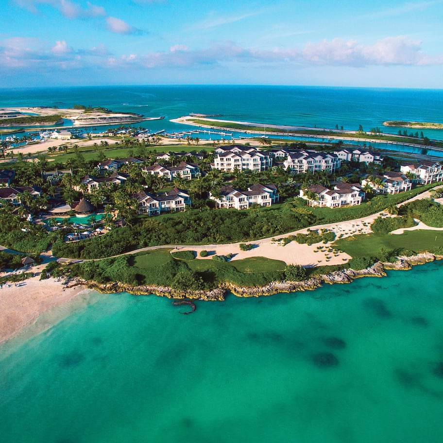 An aerial view of a coastal resort with multiple buildings, a marina, and a beach.