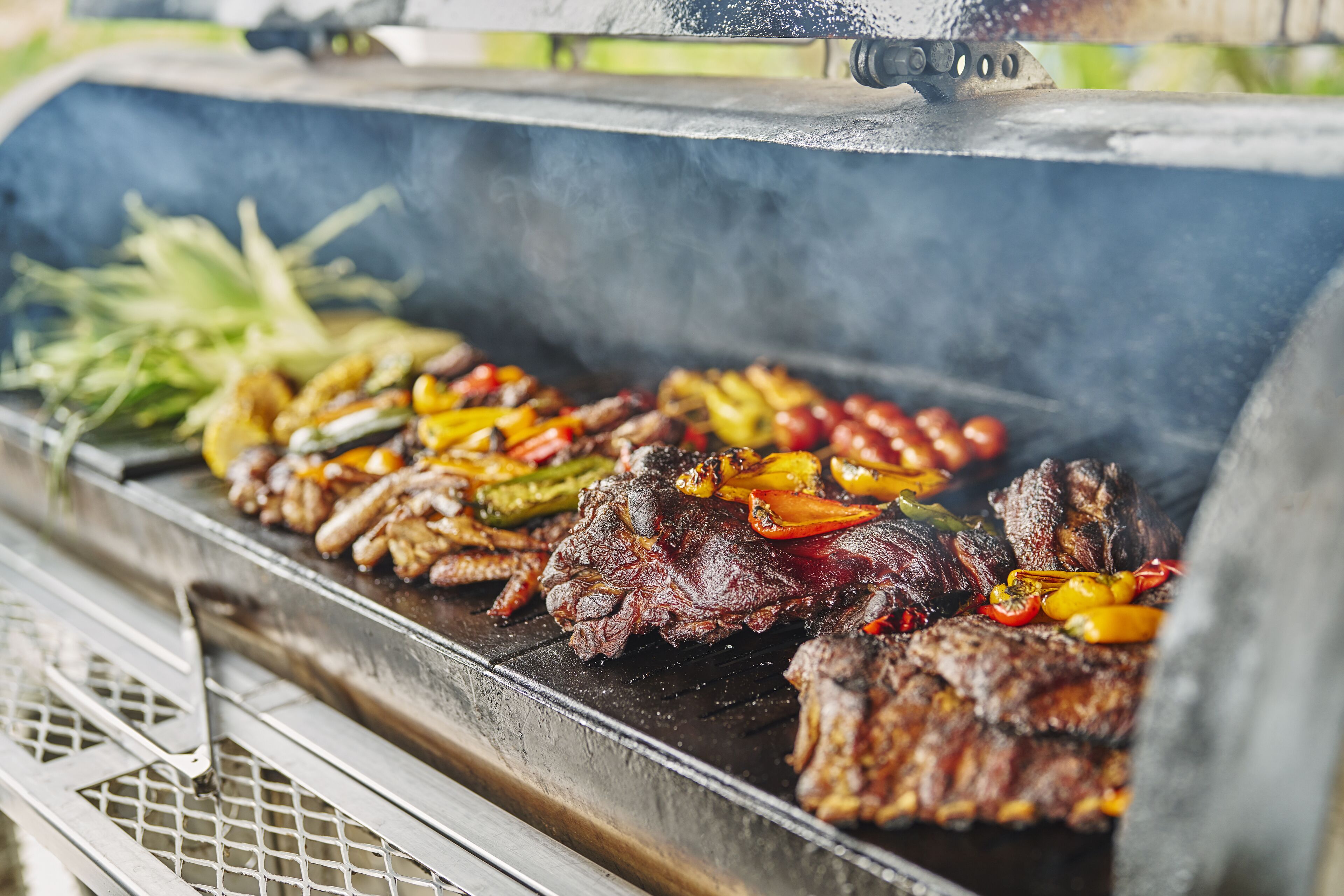 A grill with various meats and vegetables being cooked.