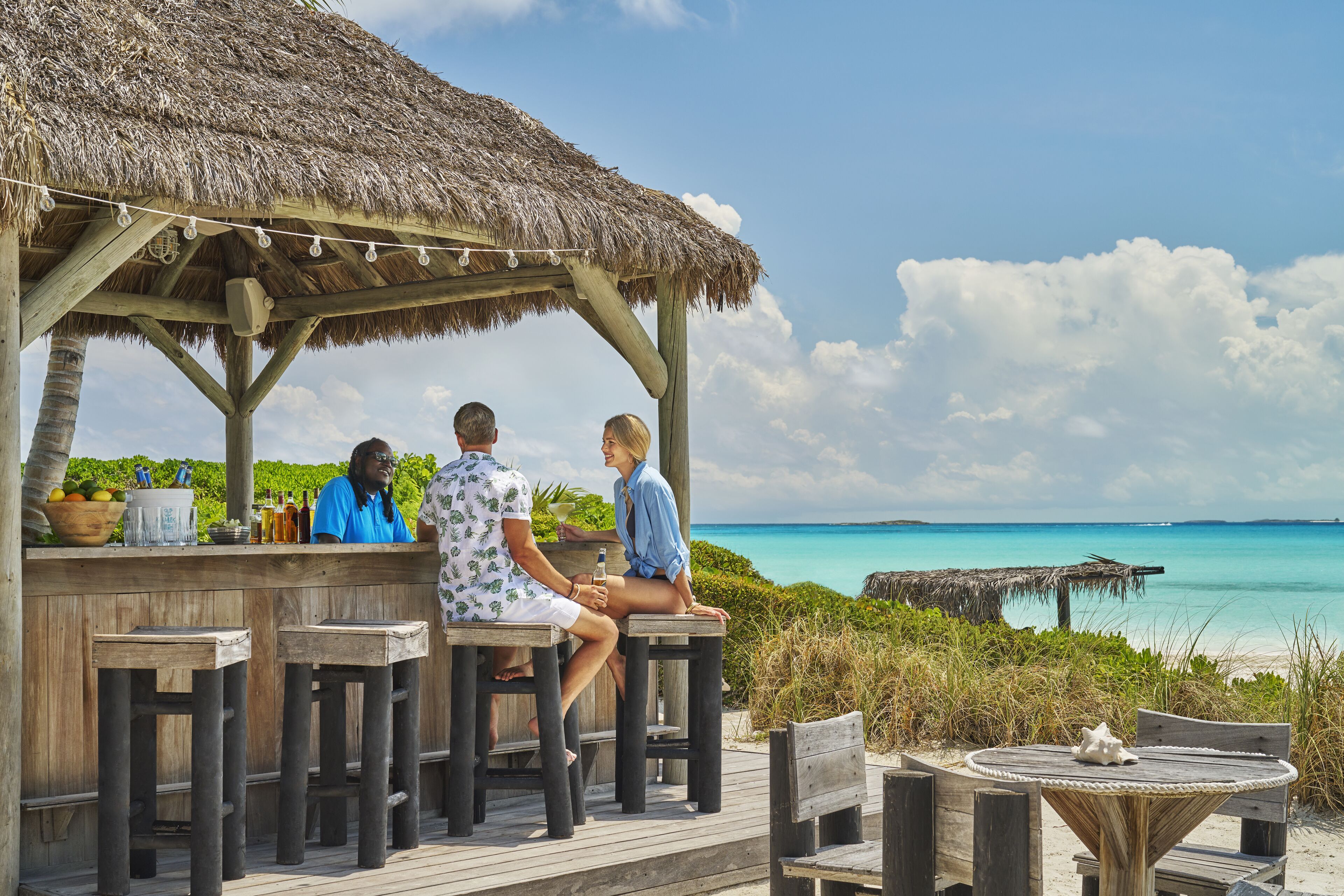 A wooden deck with a thatched roof, overlooking a turquoise sea.