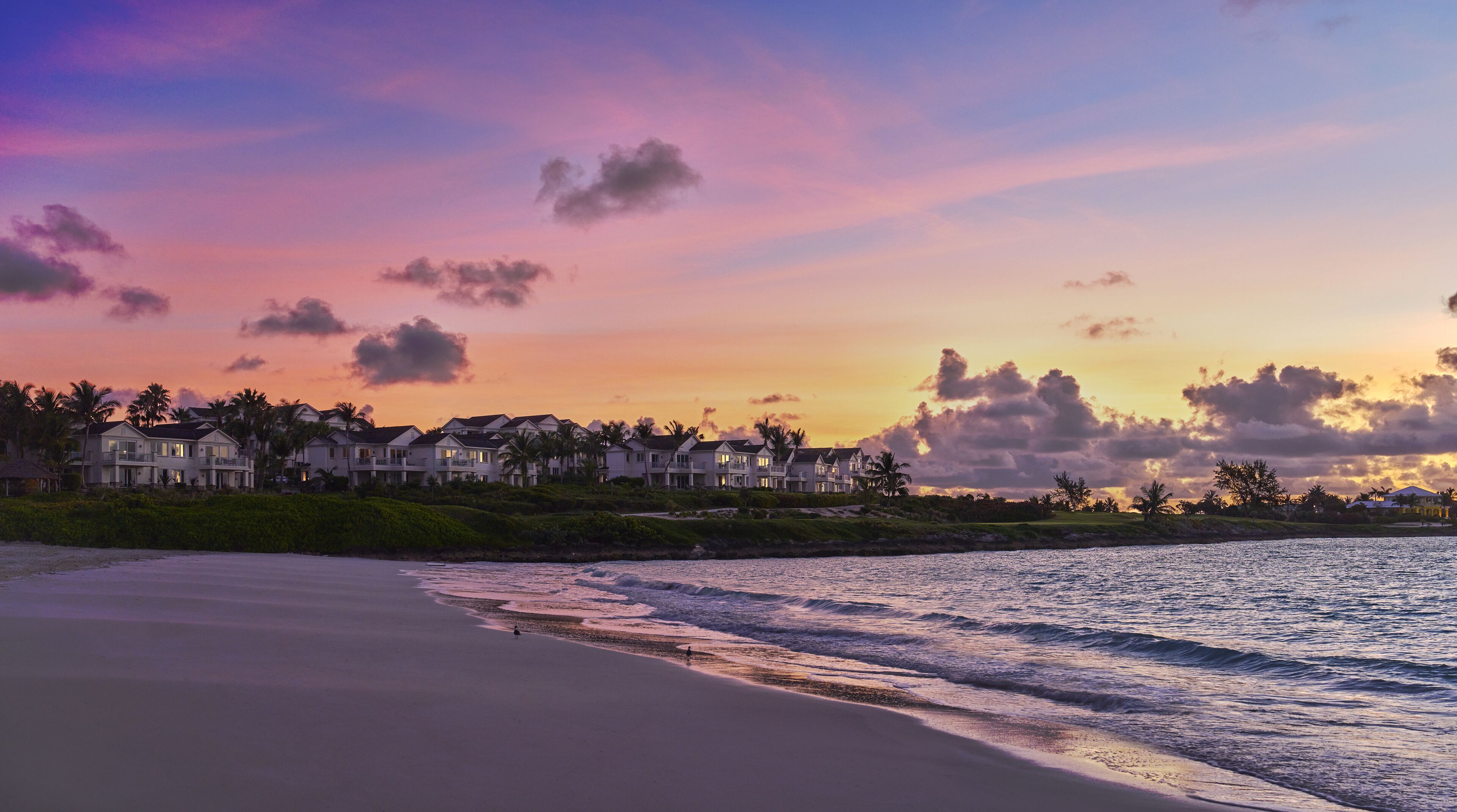 A beachfront property with multiple houses, a sandy beach, and a view of the ocean.