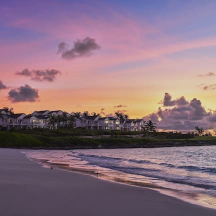 A beachfront property with multiple houses, a sandy beach, and a view of the ocean.