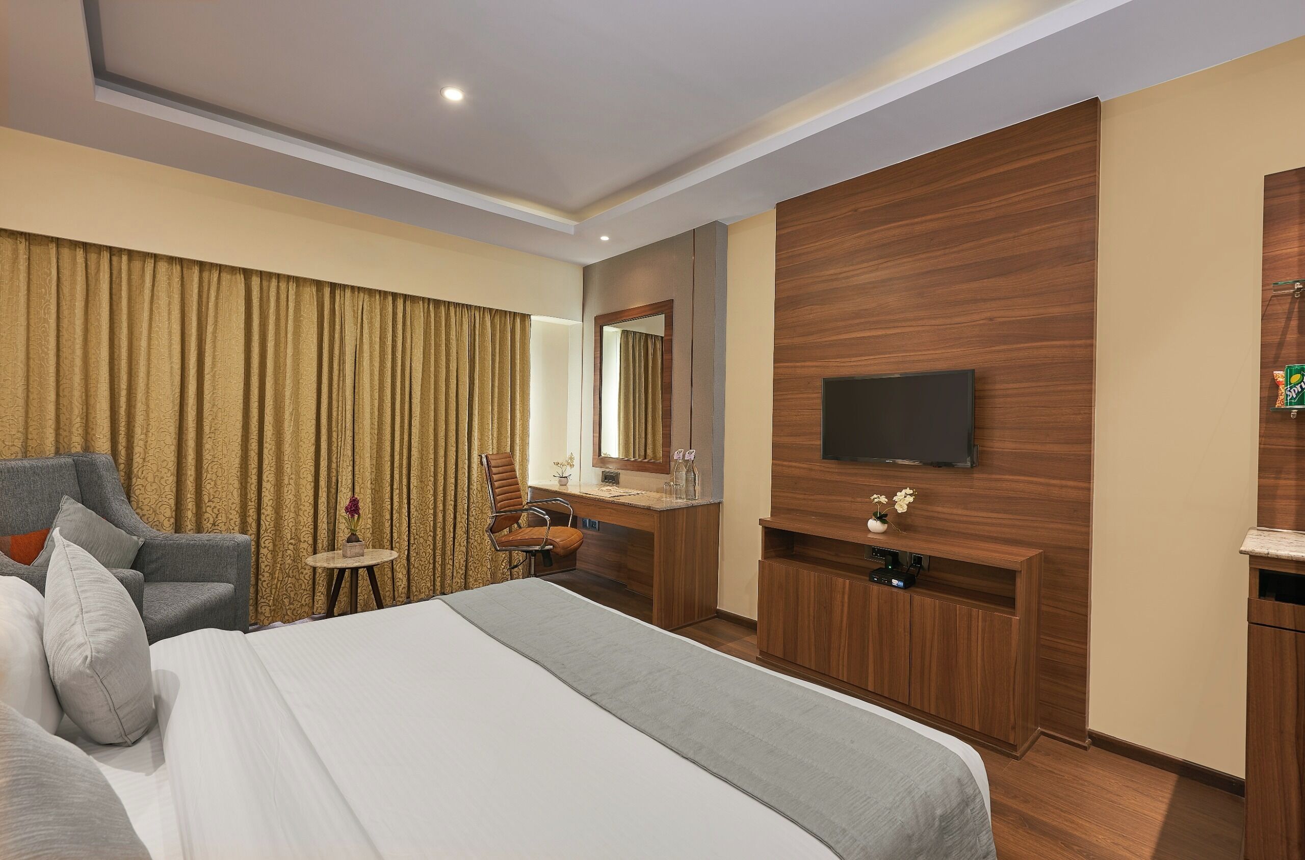 A hotel room with a bed, a desk, a chair, a television, and a mirror.