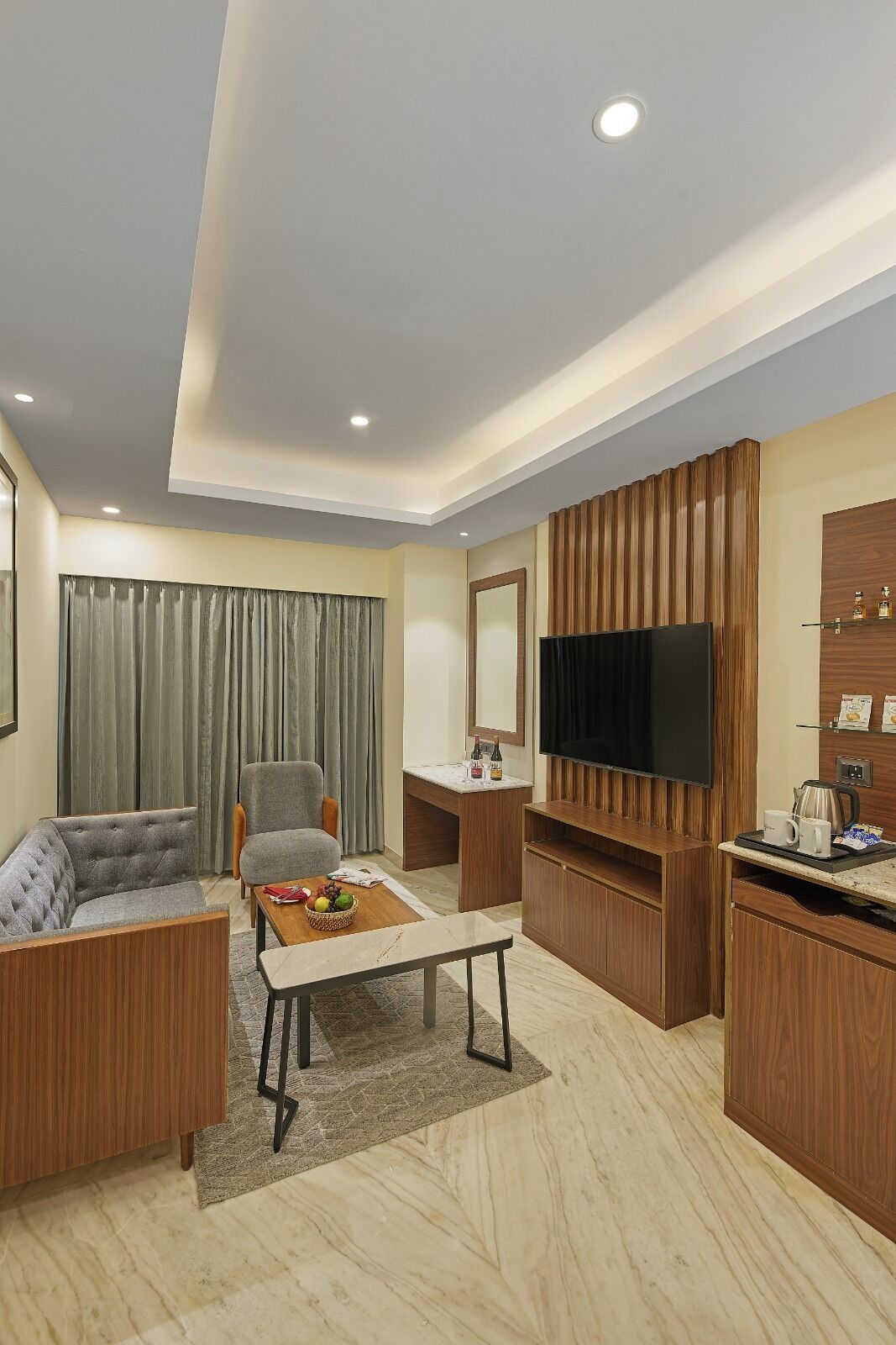 A modern living room with a sofa, armchair, coffee table, and a flat-screen TV mounted on a wooden wall.