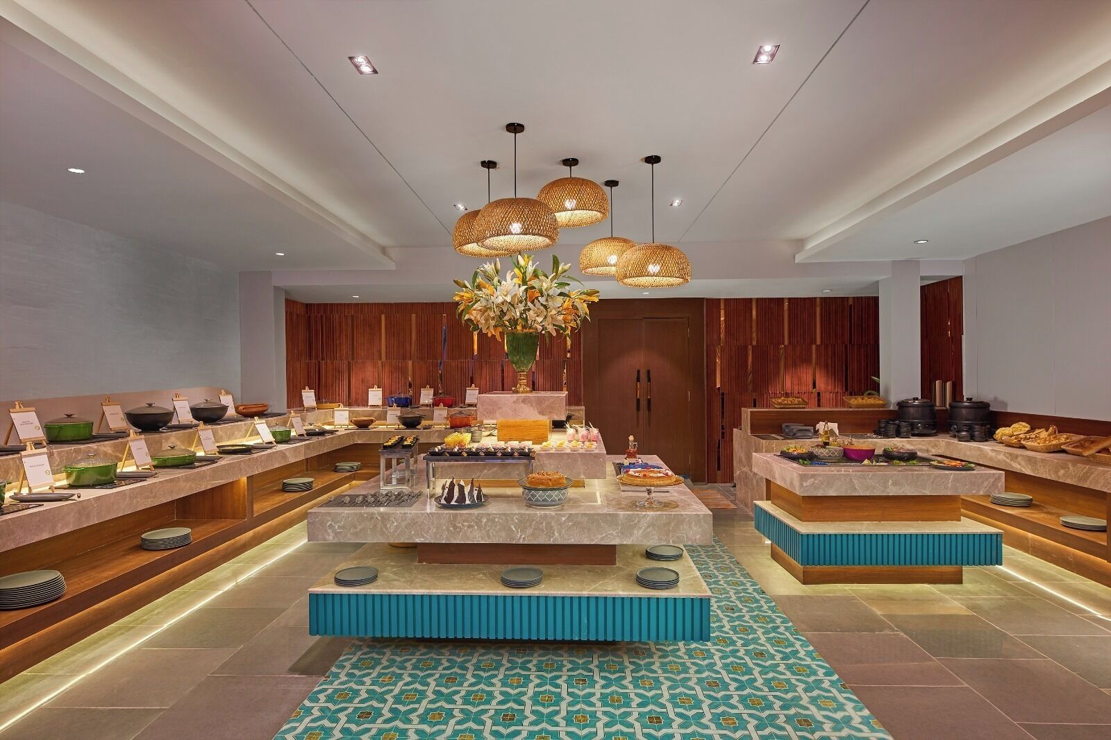 Montaje de bufé con varias estaciones de servicio, un arreglo floral central y un diseño interior moderno.
