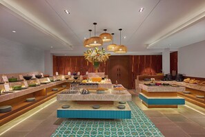 A buffet setup with multiple serving stations, a central floral arrangement, and a modern interior design. - Southernstar Bangalore (Bengaluru)