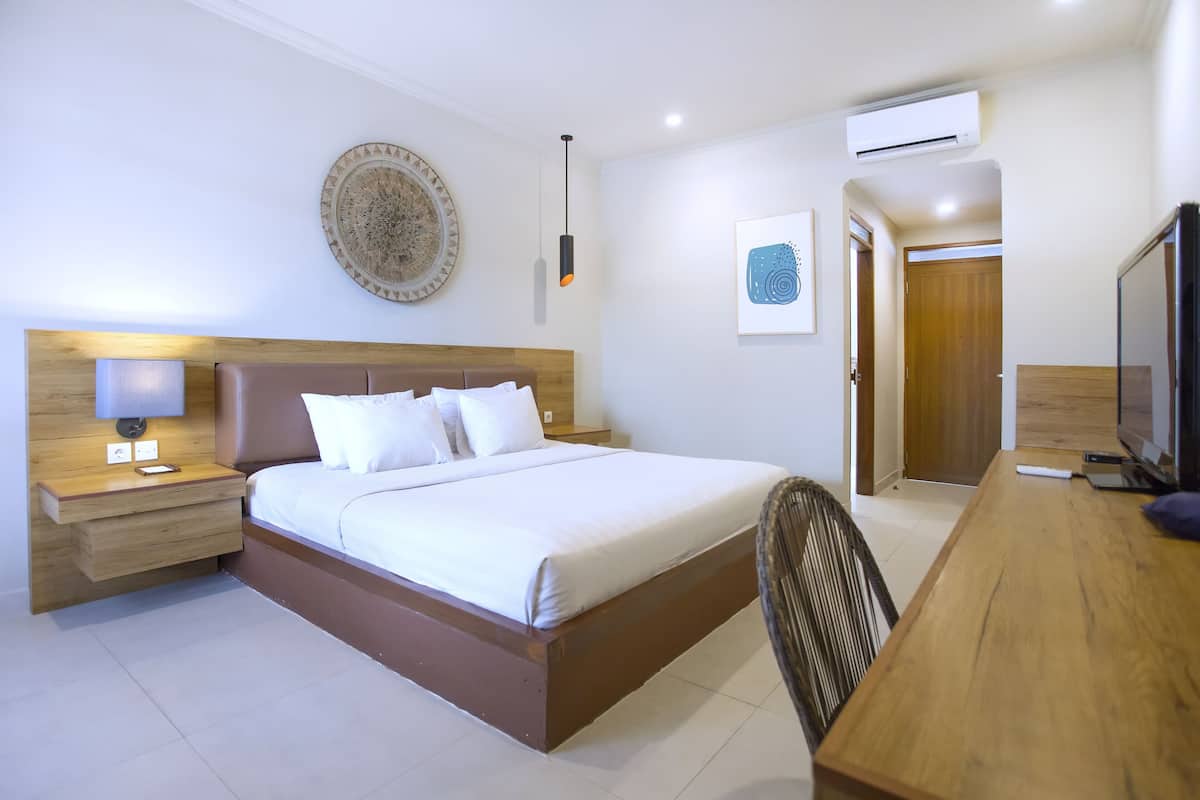 Un dormitorio con cama, mesita de noche, lámpara y televisor.