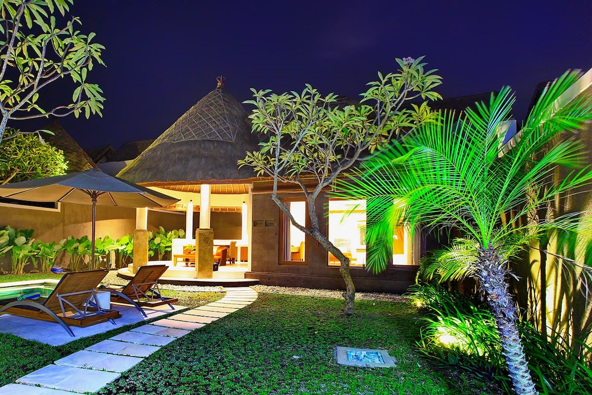 Un espacio exterior bien iluminado con piscina, sillas de descanso y zona de comedor.