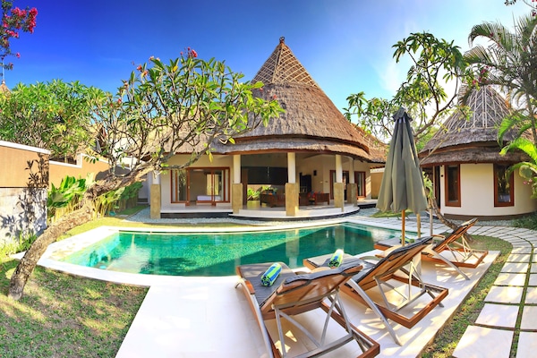 Una piscina al aire libre, sombrillas, sillones reclinables de piscina