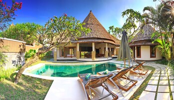 Una piscina al aire libre, sombrillas, sillones reclinables de piscina