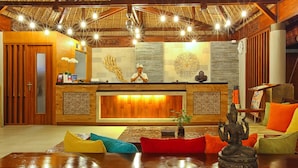 A reception area with a wooden reception desk, a receptionist, and a seating area with colorful cushions.