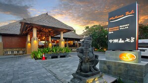 A resort entrance with a thatched roof, a statue, and a sign for Mutiyana Bali Boutique Resort Villas SPA.