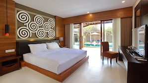 A modern hotel room with a large bed, a desk with a TV, and a view of an outdoor swimming pool.