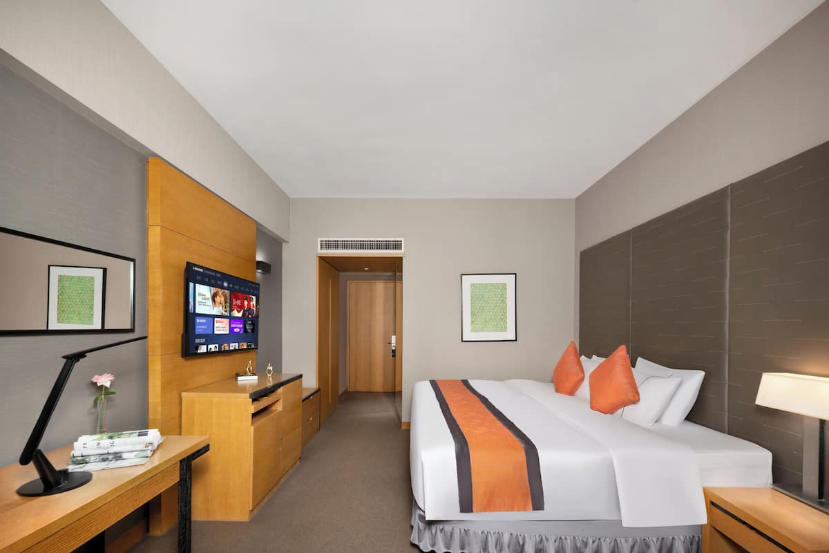 Een hotelkamer met een bed, bureau, televisie en een receptie.