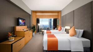 Ein Hotelzimmer mit zwei Betten, einem Schreibtisch, einem Fernseher und Blick auf die Stadt.