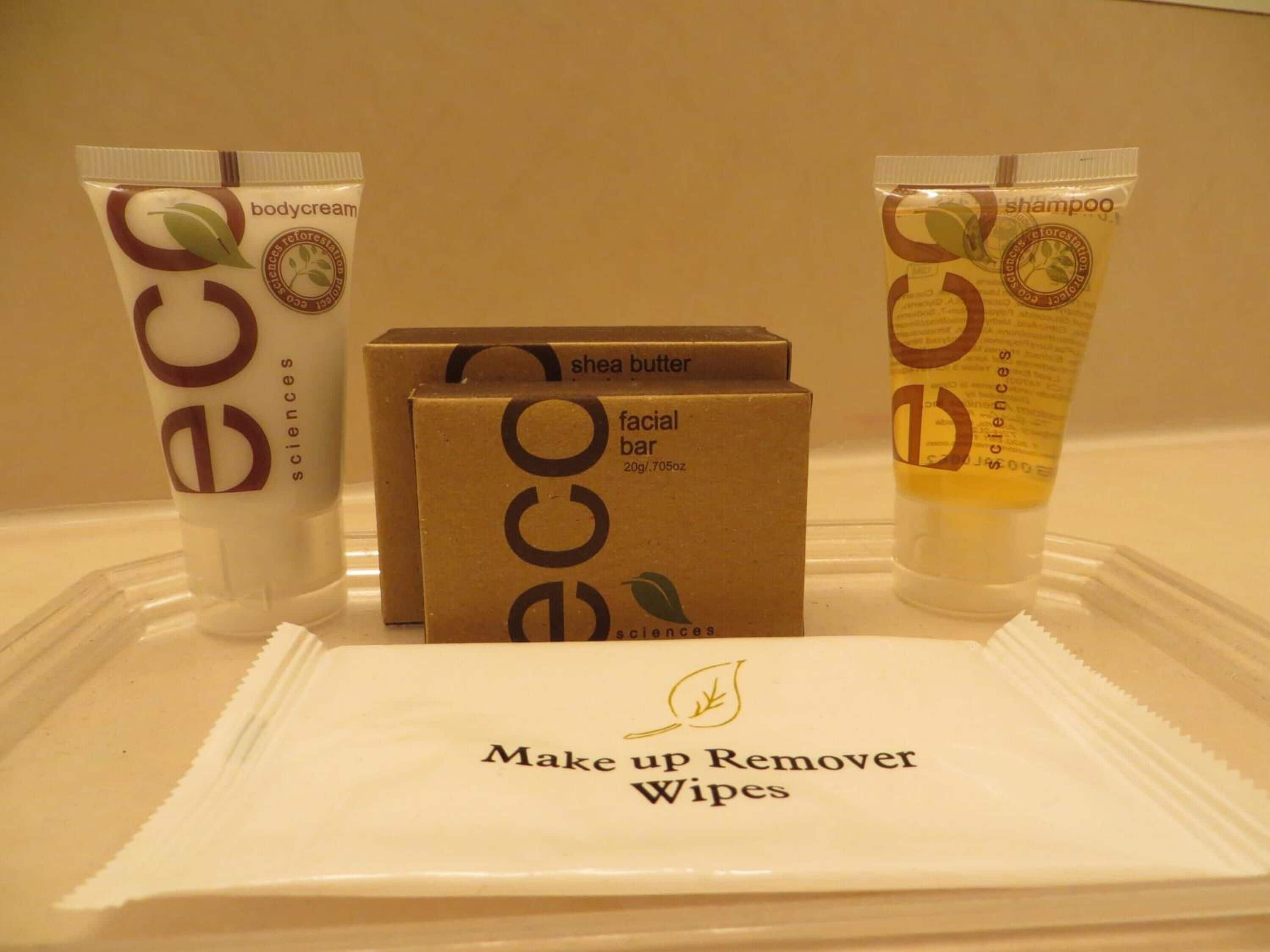 Un plateau contenant divers produits de soins personnels, notamment une crème pour le corps, un savon pour le visage et un shampooing, ainsi qu’un paquet de lingettes démaquillantes.