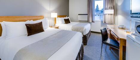 A hotel room with two beds, a desk, a chair, a TV, and a window with curtains.