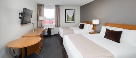 Ett hotellrum med två sängar, ett skrivbord med en stol, en tv och ett fönster med gardiner.