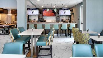 Un área de bar moderna con asientos, una pantalla de televisión y una barra.