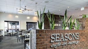 A restaurant interior with a brick wall, hanging pendant lights, and indoor plants. - Heritage Inn Hotel & Convention Centre Taber (Taber)