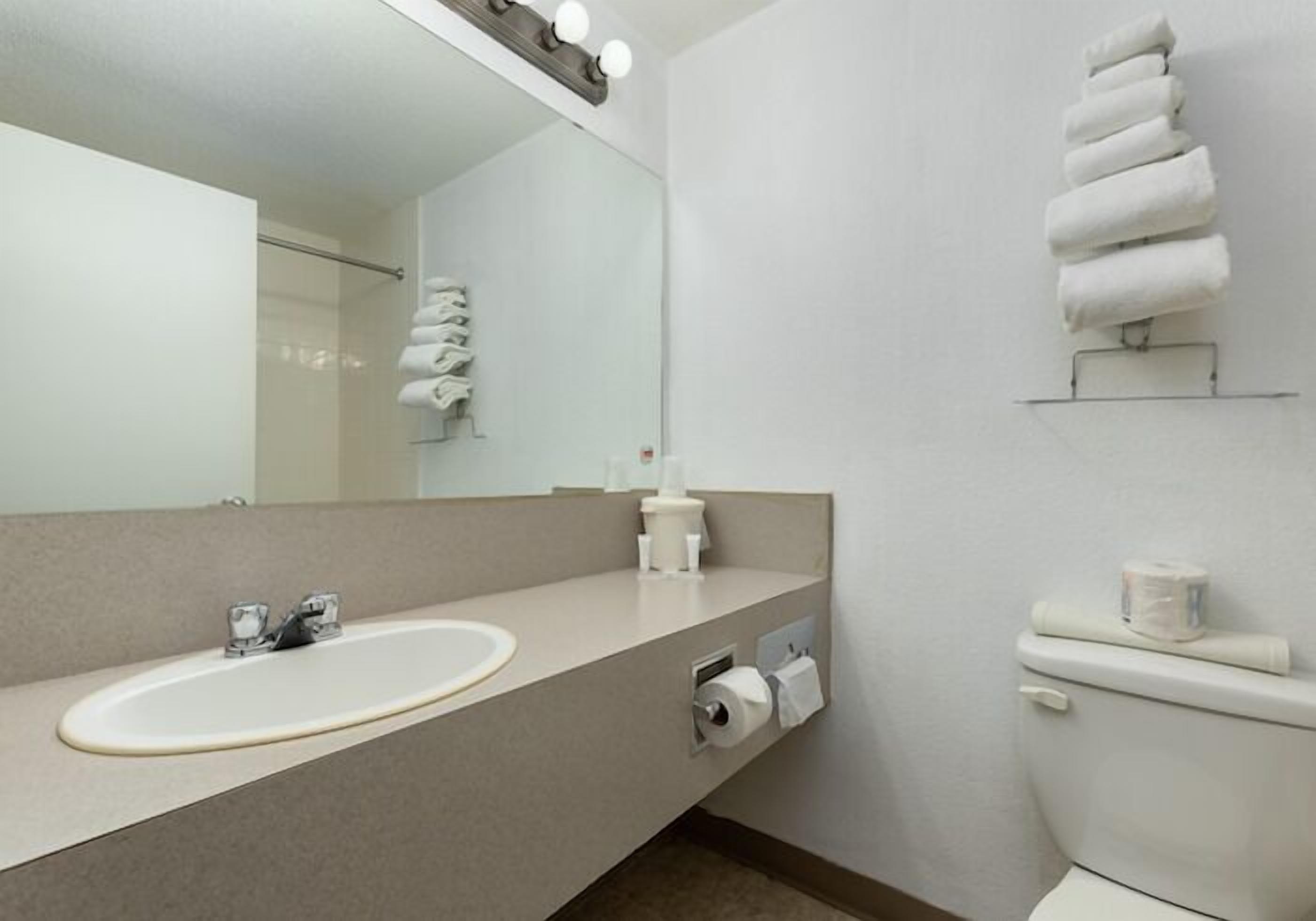 A modern bathroom with a large mirror, a sink, a toilet, and a towel rack.