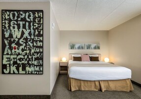 A bedroom with a bed, two bedside tables, and a wall art piece.