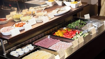 Ein reichhaltiges Buffet mit verschiedenen Speisen, darunter Fleisch, Käse und Gemüse.