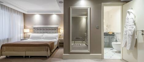 Quarto de hotel com cama grande, mesa de cabeceira, espelho, closet espaçoso e banheiro com vaso sanitário e pia.