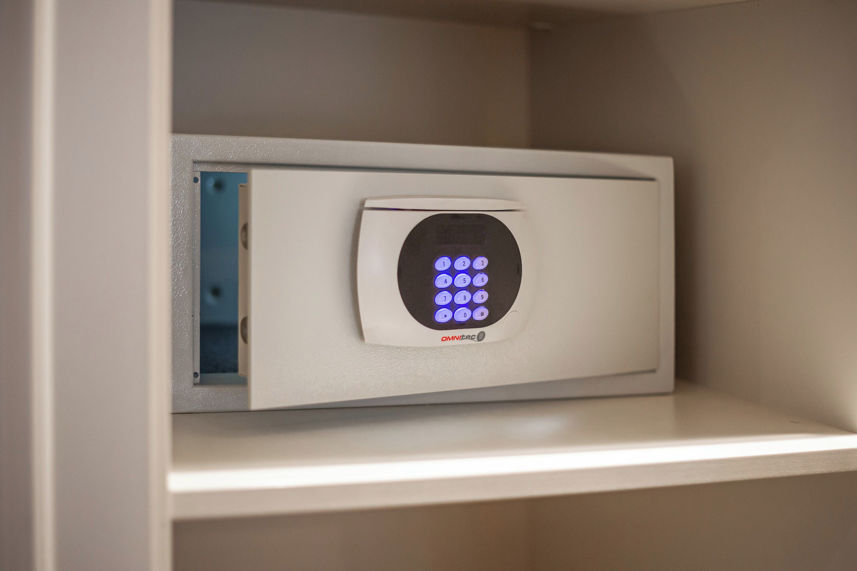 A security keypad with a blue light indicator, located in a white-framed panel, likely part of a door or access point.