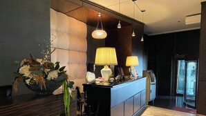 Et receptionområde med marmorgulv, en reception, en vase med blomster og en lysekrone.