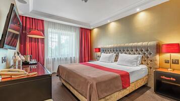 Habitación de hotel con una cama grande, un escritorio con espejo, una lámpara y una mesita de noche.
