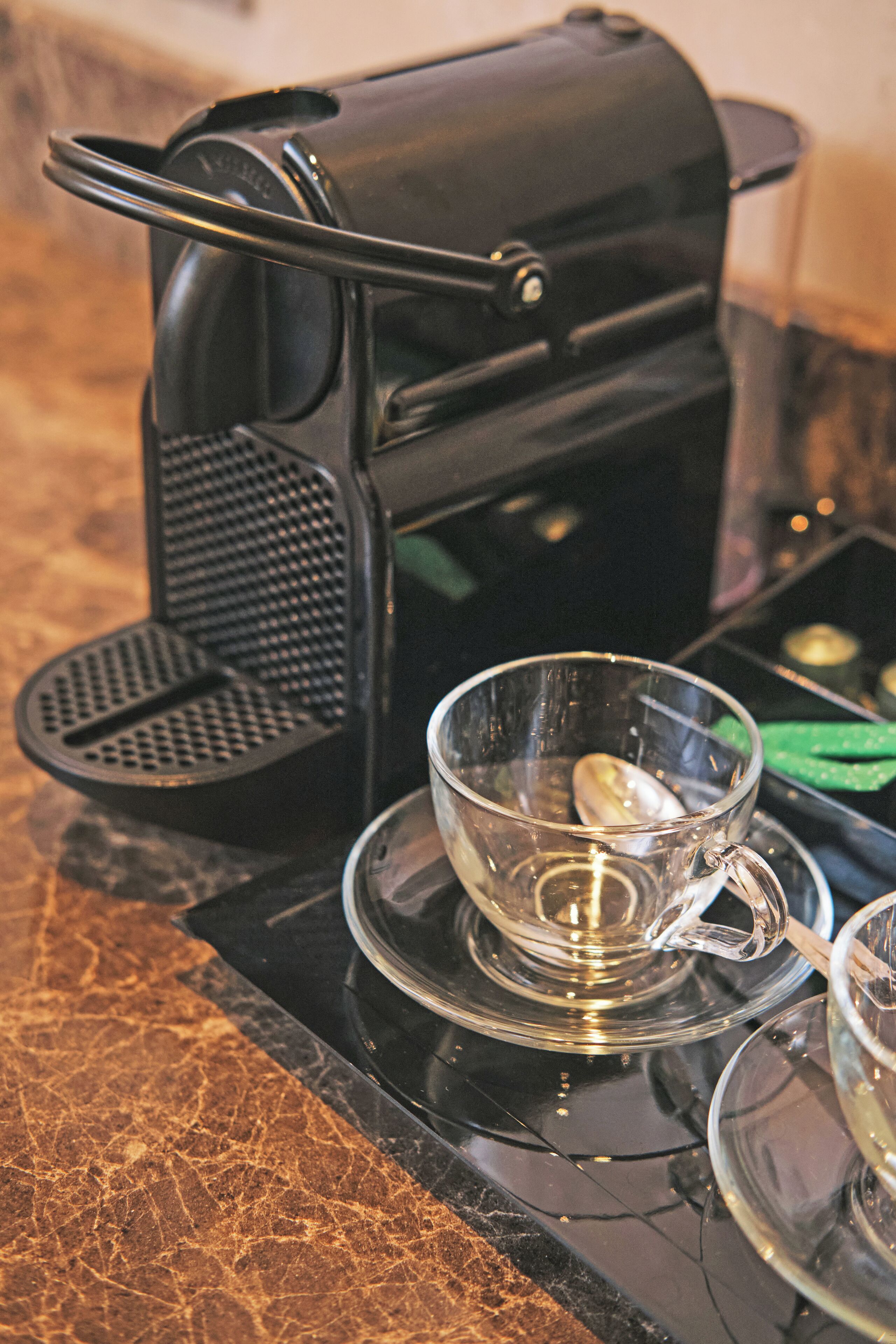 A coffee maker with a glass cup on a marble countertop.