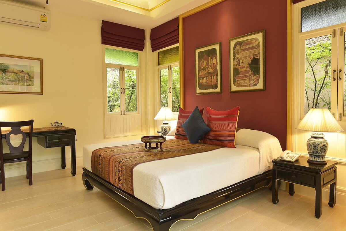 A neatly arranged bedroom with a bed, bedside tables, a chair, and artwork on the walls.