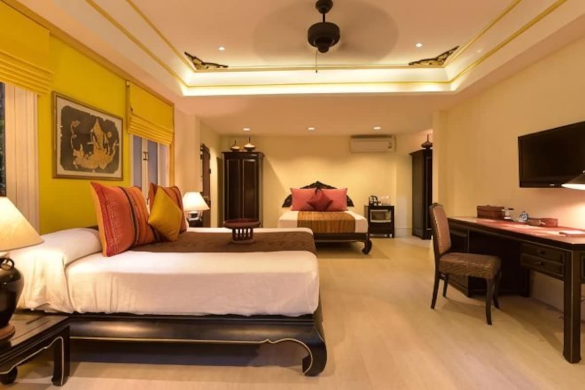 A hotel room with a bed, desk, chair, and a television.