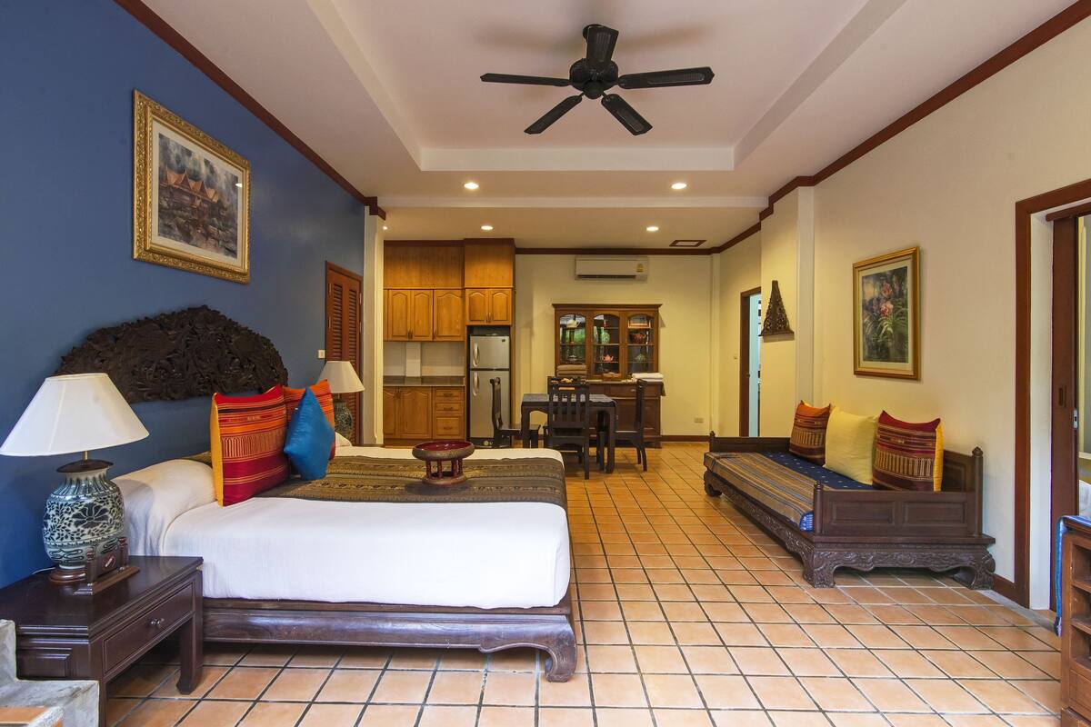A hotel room with a bed, bedside table, lamp, and a ceiling fan.
