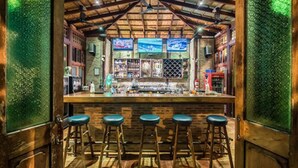 Un espace bar avec un plafond en bois, des panneaux de verre verts et trois tabourets.