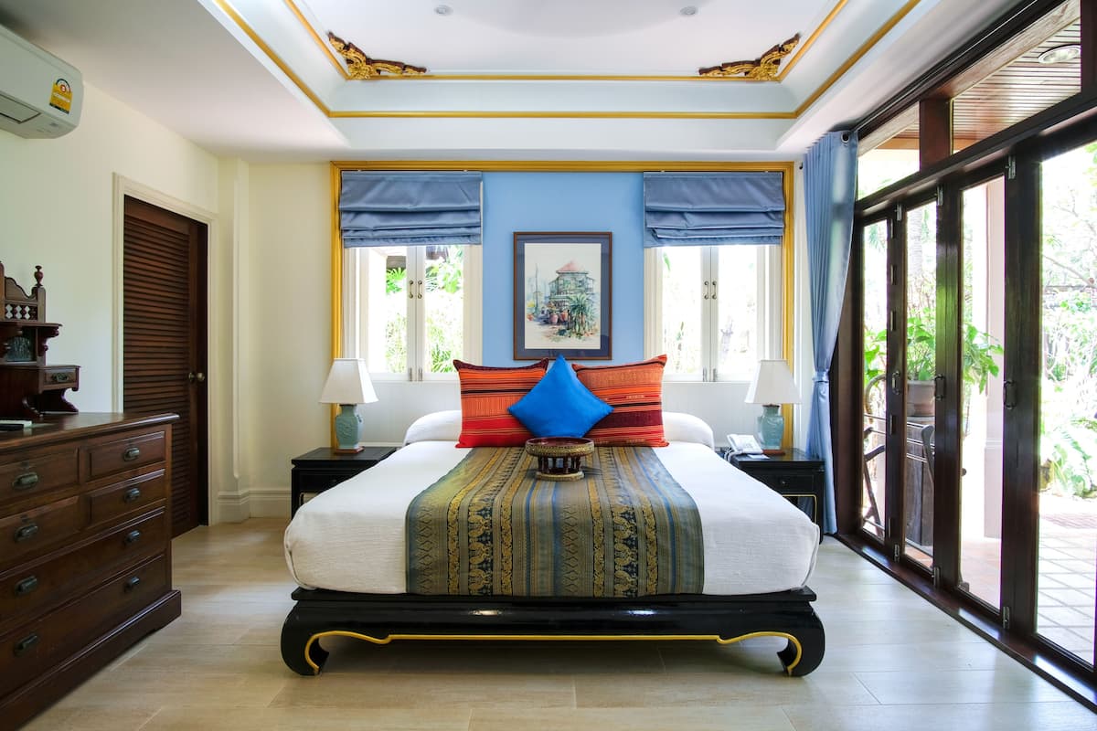 A spacious bedroom with a large bed, a dresser, and a window with curtains.