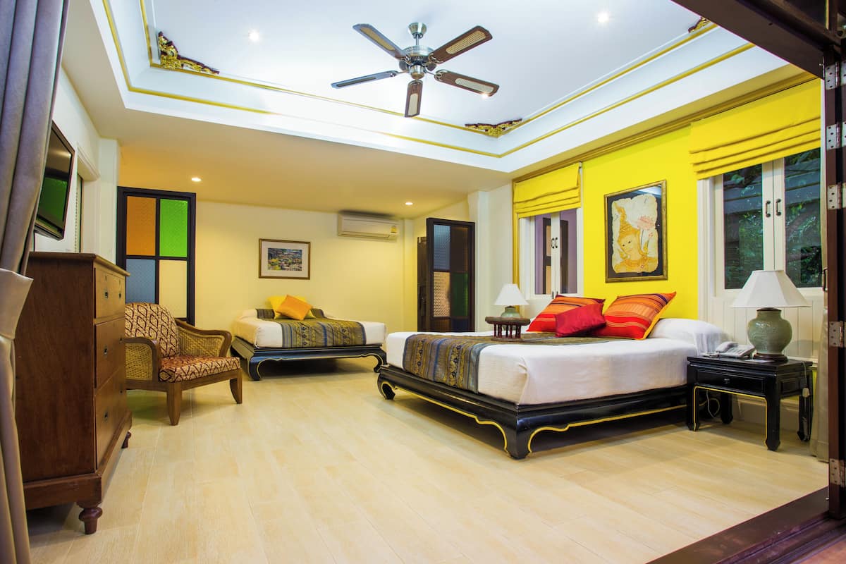 A hotel room with a bed, a chair, a desk, and a ceiling fan.