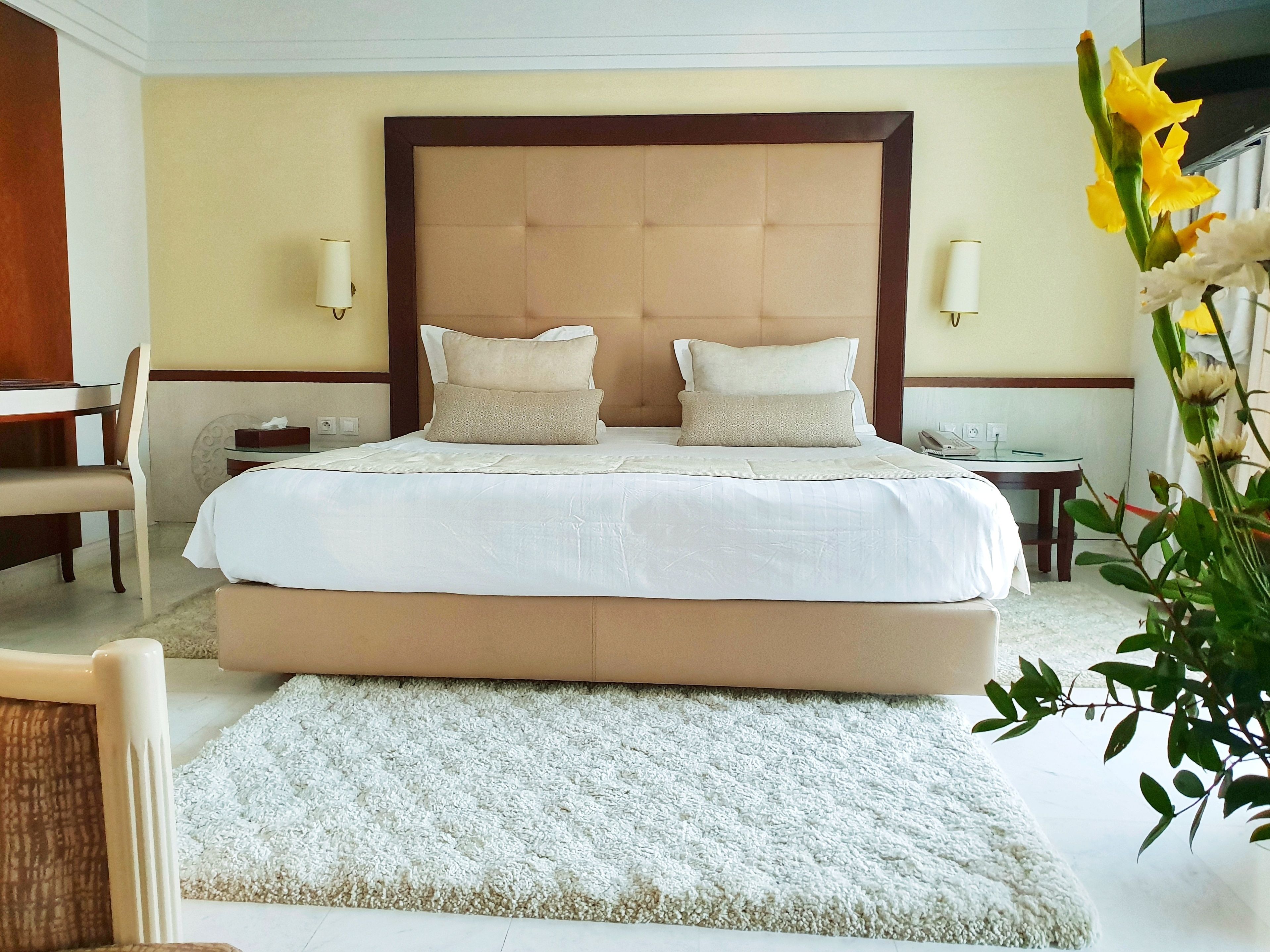 A hotel room with a large bed, two bedside tables, a chair, and a small desk.