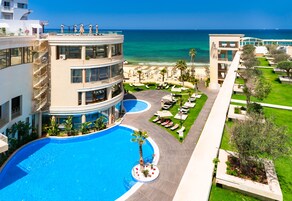 Un hotel con piscina, vistas a la playa y varios pisos.