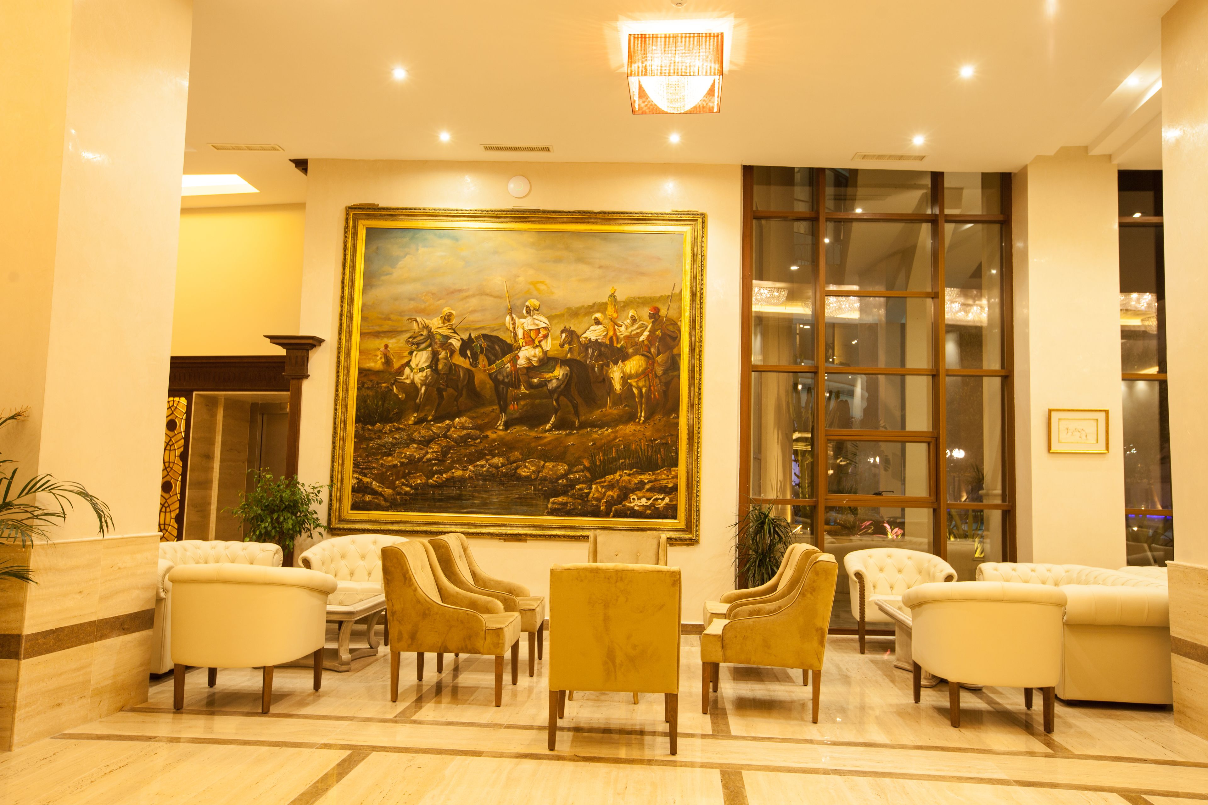 A lobby with a large painting, several sofas, and a chandelier.