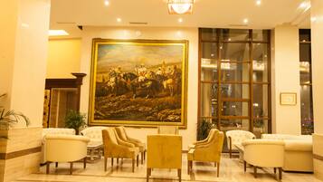 A lobby with a large painting, several sofas, and a chandelier.