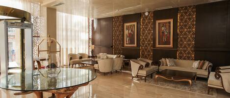 A spacious living area with a glass-top coffee table, comfortable sofas, and a decorative wall with framed artwork.