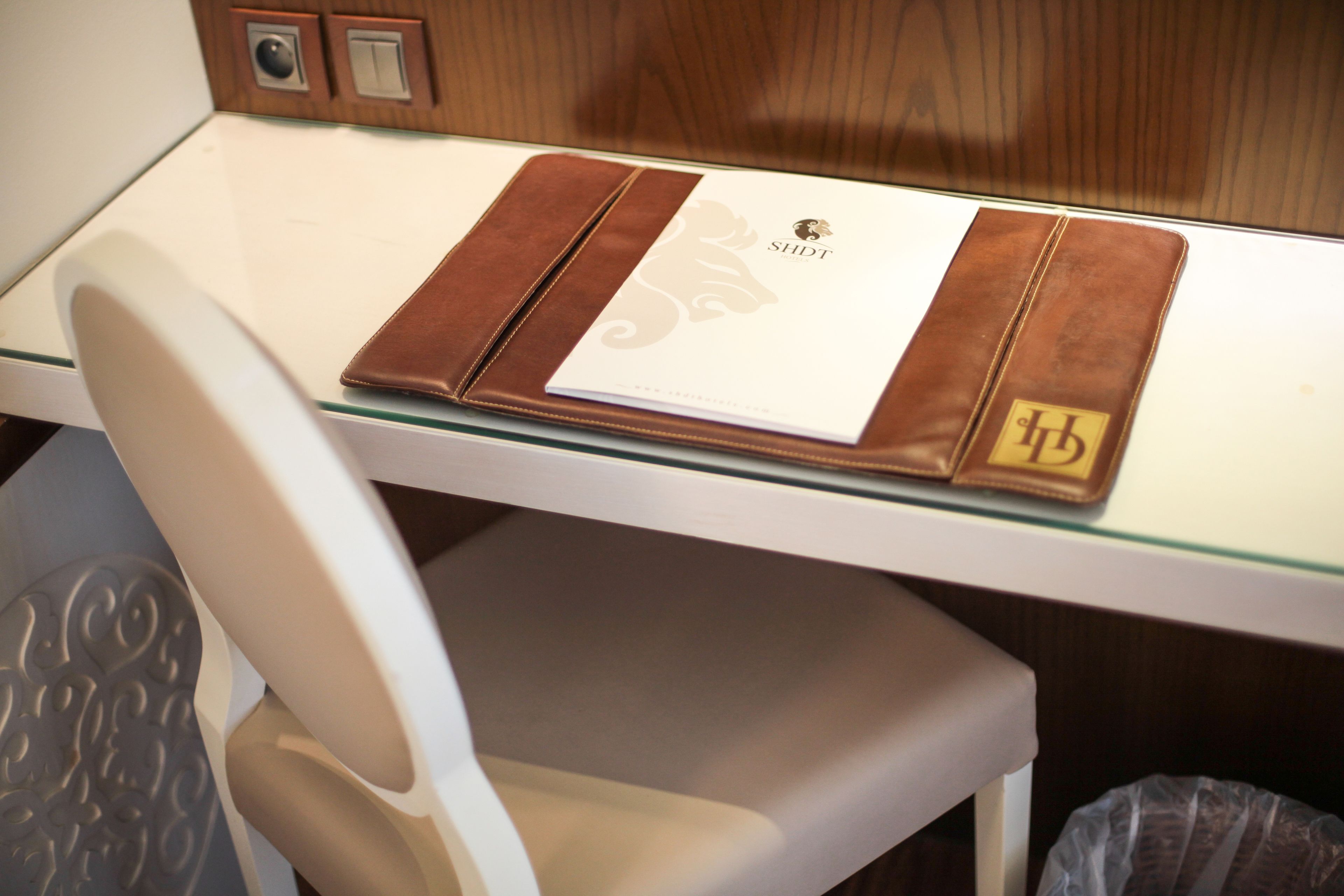 A white table with a leather folder containing a document and a logo.