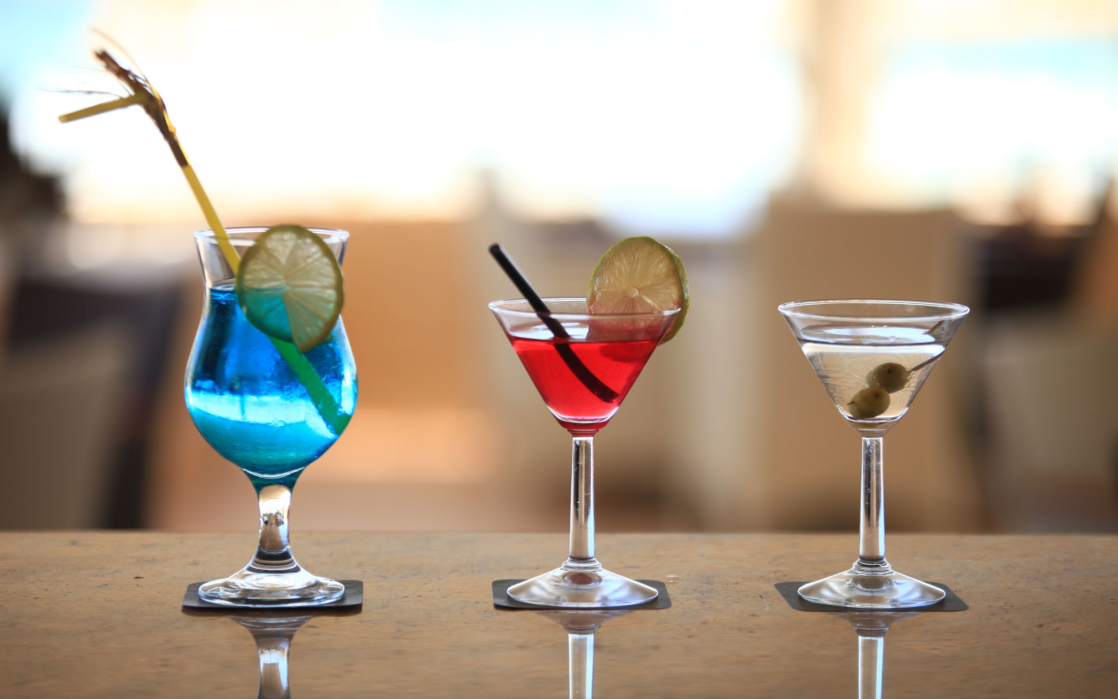 Tres cócteles diferentes en copas tipo martini sobre una mesa de madera.