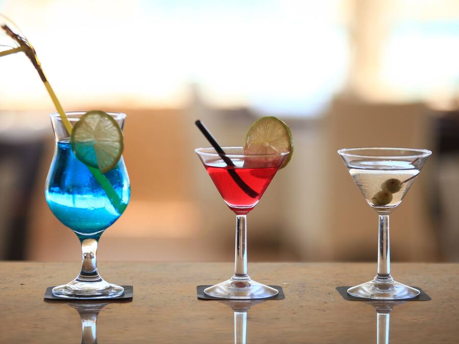 Three different cocktails in martini glasses on a wooden table.