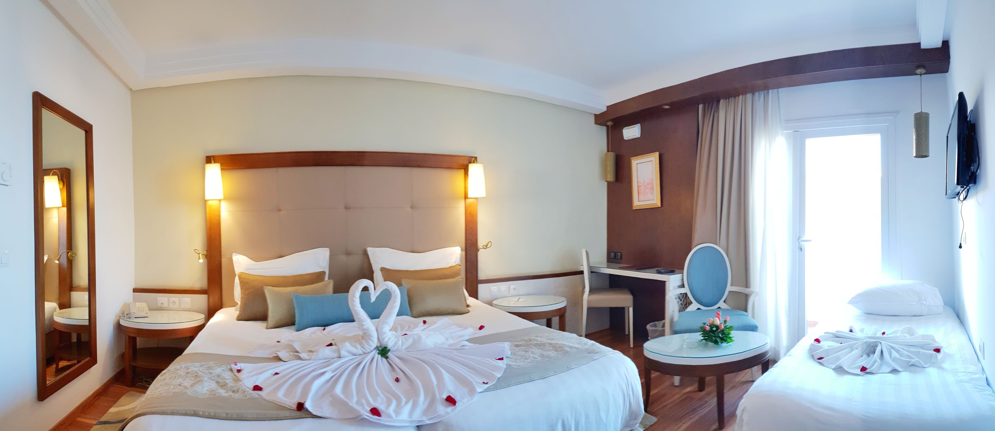Una habitación de hotel con una cama grande, un escritorio, una silla, una mesa redonda y un televisor.