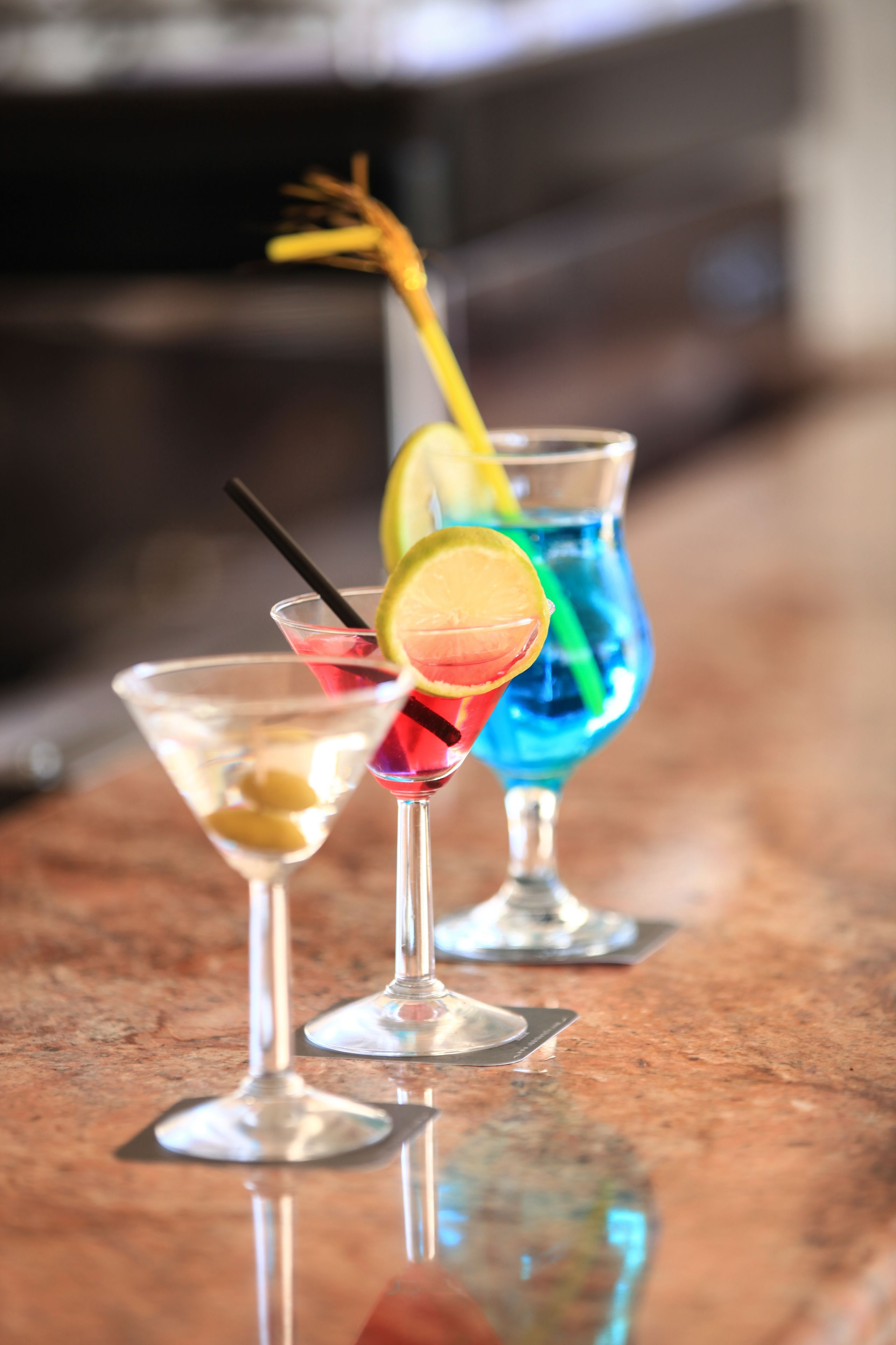 Three cocktails on a reflective surface.