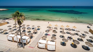 A beach with thatched umbrellas, sun loungers, and wooden cabanas. - Sousse Palace Hotel & Spa (Sousse)