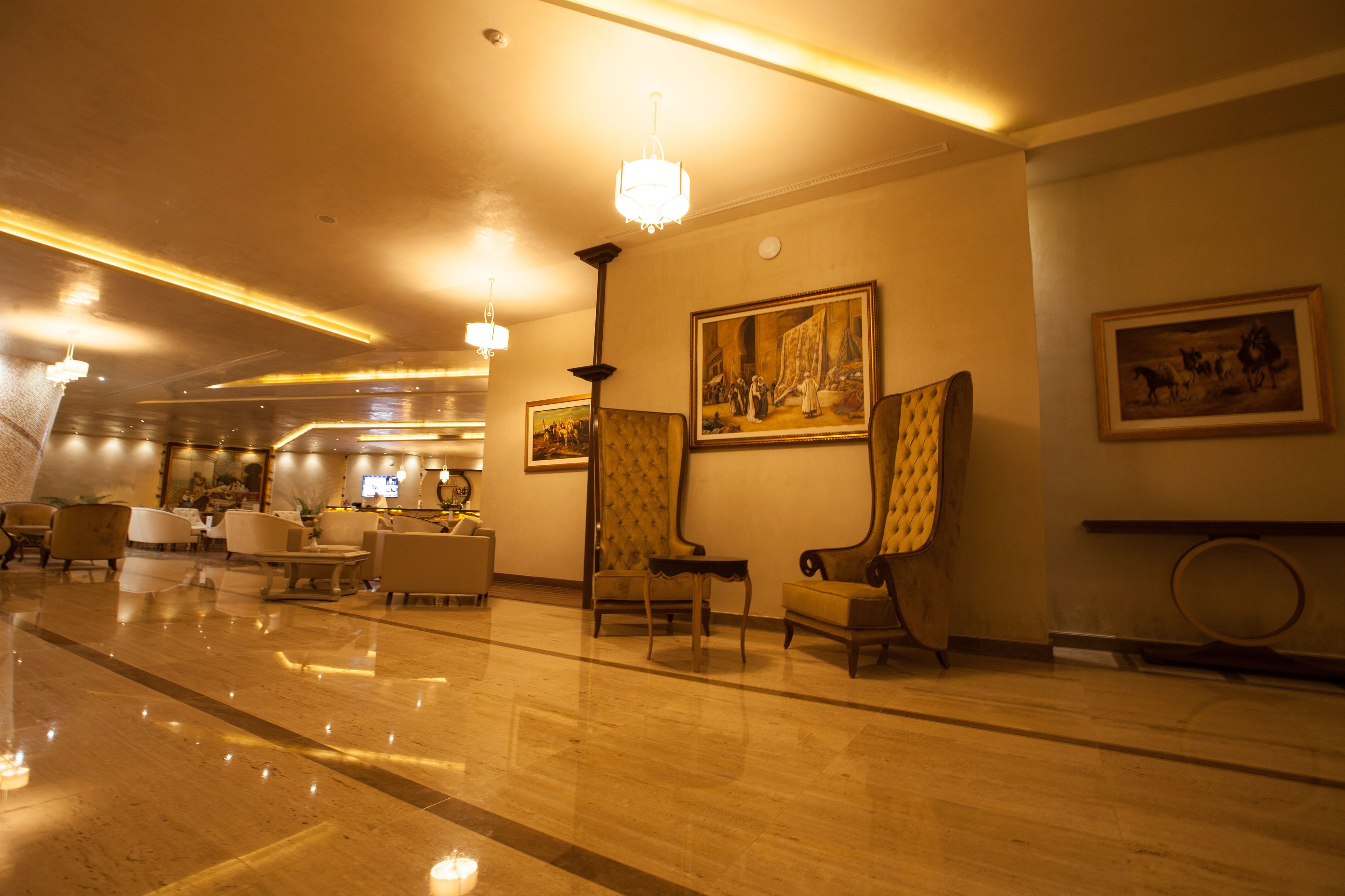 A hotel lobby with a polished marble floor, several seating areas, and artwork on the walls.