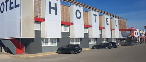Een motel met meerdere kamers, een parkeerplaats en een paar geparkeerde auto's voor de deur.